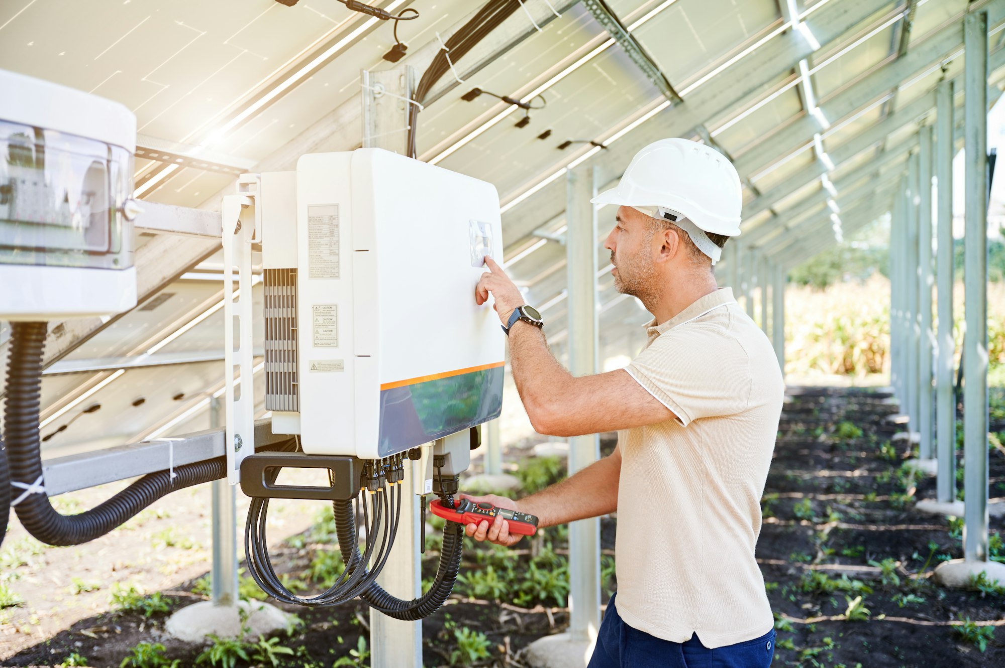 Professional worker checking voltage on solar inverter.